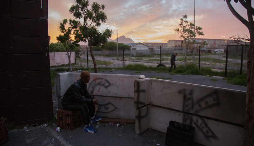 An alleged Clever Kids gangster sits behind a number of upturned benches that are used as a shooting barricade during skirmishes with rival gangs in Manenberg, Cape Town.

