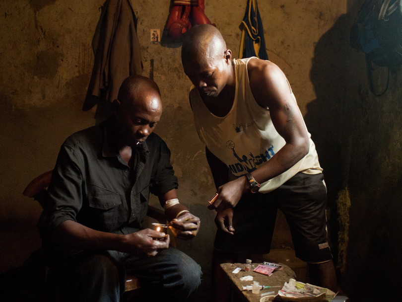 In a slum in Kampala, Uganda, two men prepare to inject heroin. Usually users prefer smoking the drug due to the risk of overdose and disease associated with injecting.
