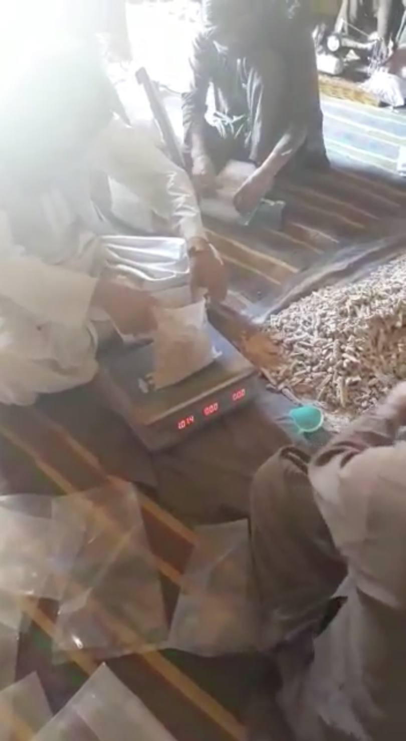 Still from a video purportedly showing heroin being packaged on the Pakistan– Afghanistan border. The heroin is scooped from the central pile (middle right) into one-kilo bags (such as that placed on the scale in the centre). Similar packaging and drug texture were subsequently seen in a sample of heroin by GI-TOC researchers in Durban.
