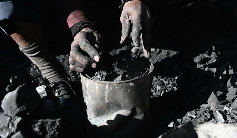 A charcoal trader packs charcoal in small tins for sale in Nairobi in 2019. The charcoal market in Nairobi can be described as a ‘grey market’, as legally imported charcoal is sold along with – and indistinguishable from – charcoal that has been illicitly produced.
