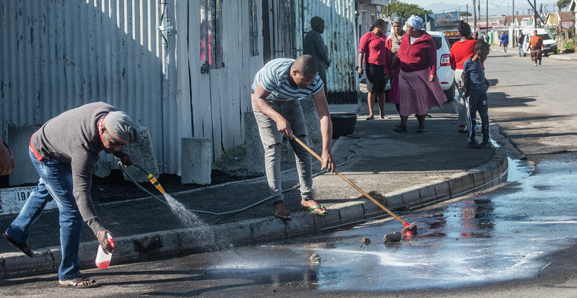 Family members wash blood off the street after a shooting incident in Khayelitsha, May 2022.
