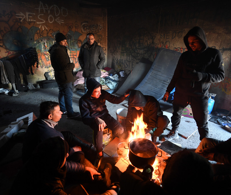 Asylum-seekers keep warm in an abandoned building at Bira camp in Bihac.

