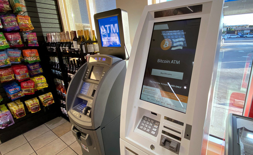 Bankomat bitkoini pranë një bankomati të zakonshëm në një pikë karburanti.
