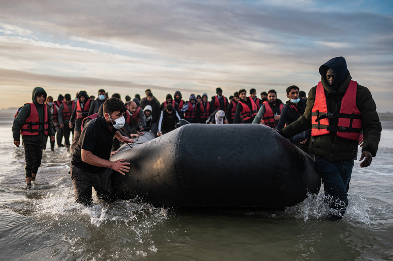 Emigrantët shtyjnë drejt ujit një gomone pasi kanë zbarkuar në plazhin e Gravelinit, pranë Dunkirkut, në veri të Francës, më 12 tetor 2022, në përpjekje për të kaluar Kanalin Anglez.

