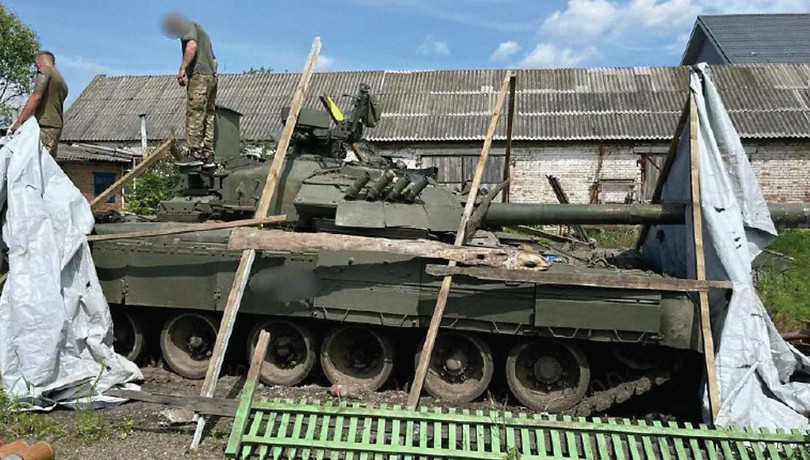 Ukrainian law enforcement reveal a Russian T-80 tank that had been concealed in a yard, July 2023.
