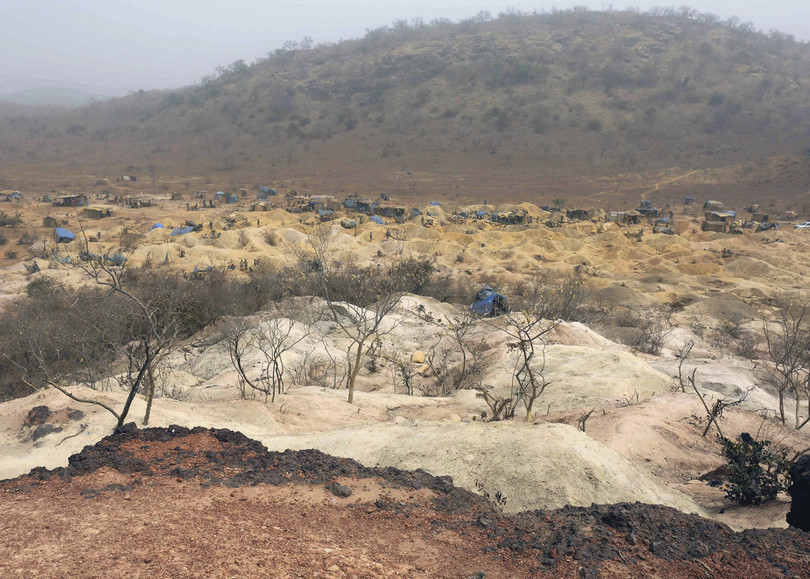 A photograph of open ground, dead vegetation, blue tents. A second photo shows a square hole in open ground.
