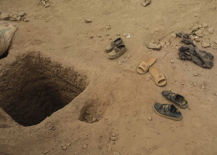 A photograph of open ground, dead vegetation, blue tents. A second photo shows a square hole in open ground.
