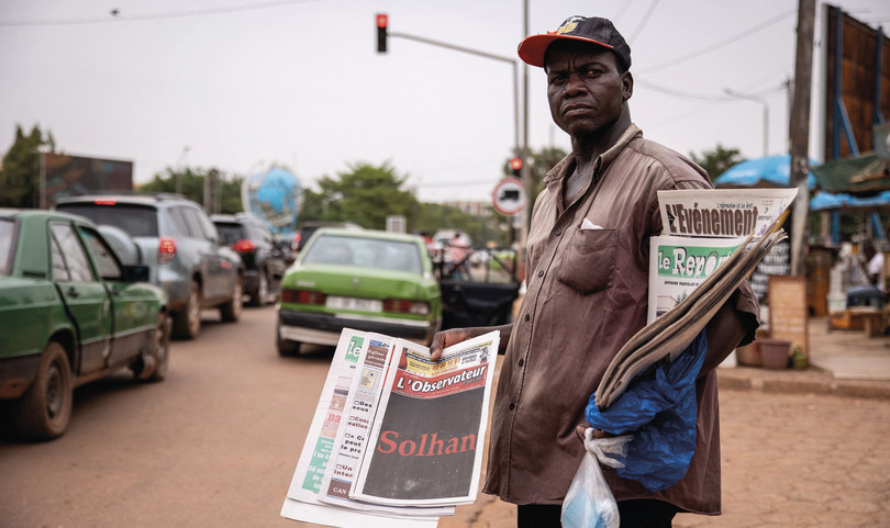 A newspaper vendor in Ouagadougou sells a local newspaper headlining the story of the Solhan massacre of 5 June 2021.

